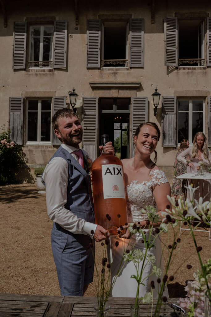 Bruiloft in Frankrijk : bruidspaar houdt samen fles rosé vast