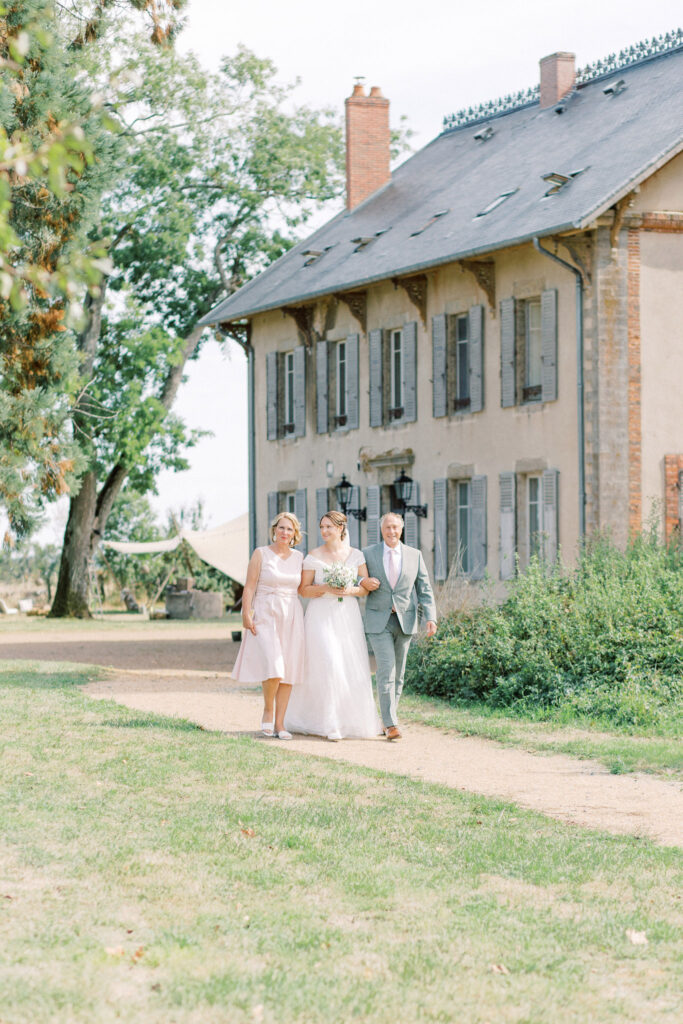 Bruid loopt naar ceremonie met ouders | Trouwen in Frankrijk