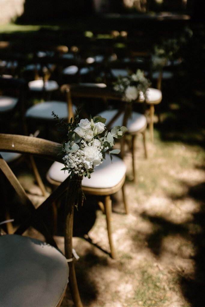 Bloemen aan stoelen bij trouwceremonie